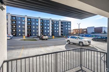 A white car is parked in a parking lot in front of a building.